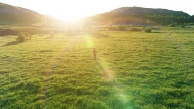 Mükemmel yeşil çayır üzerinde uçan bir sporcu. Dağda gün batımı