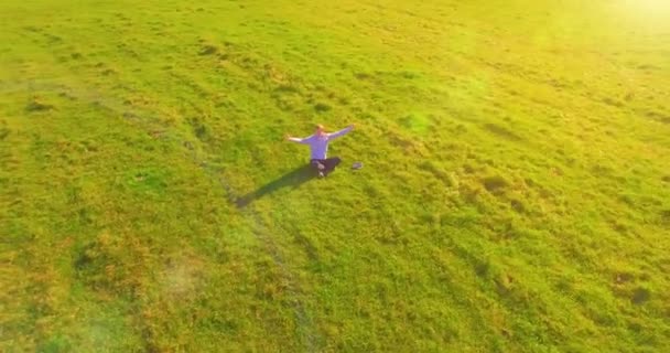 Vol orbital bas autour de l'homme sur herbe verte avec bloc-notes au champ rural jaune. — Video