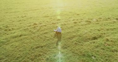 UHD 4k havadan görünümü. Defter pad ile yeşil çim sahasında oturan işadamı üzerinde düşük yörünge uçuş