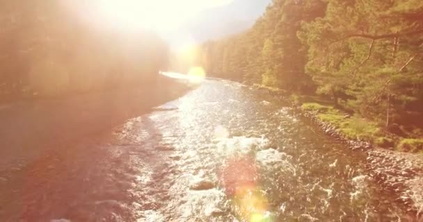 Vol à basse altitude au-dessus d'une rivière de montagne fraîche et rapide avec des rochers au soleil matin d'été. — Video