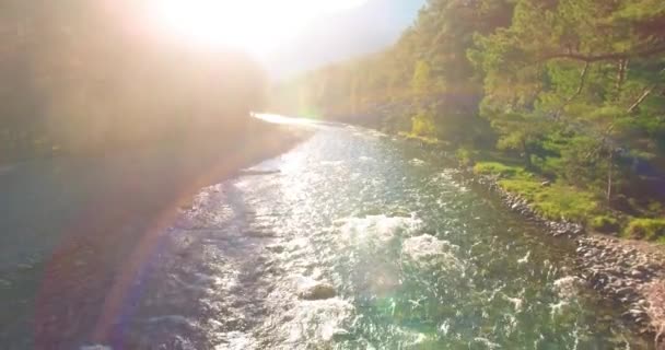 Vol à basse altitude au-dessus d'une rivière de montagne fraîche et rapide avec des rochers au soleil matin d'été. — Video