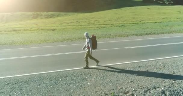 Flyg över liftare turist promenader på asfalterad väg. Enorm lantlig dal på sommardagen. Ryggsäck vandring kille. — Stockvideo