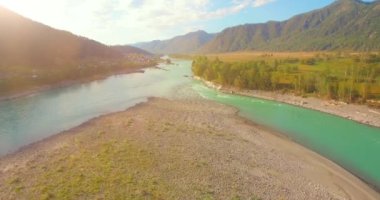 Güneşli yaz sabahında kayalarla birlikte taze, hızlı dağ nehri üzerinde alçak irtifa uçuşu..