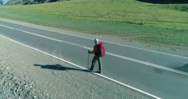 Asfalt yolda yürüyen otostopçu turist üzerinden uçuş. Yaz günü büyük bir kırsal vadi. Sırt çantalı gezgin..