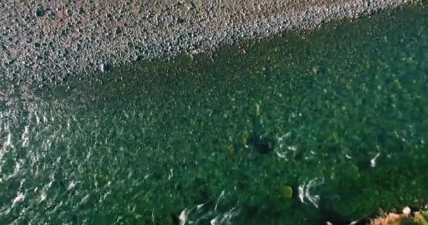 Vol à basse altitude au-dessus d'une rivière de montagne fraîche et rapide avec des rochers au soleil matin d'été. — Video