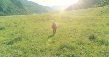 Sırt çantasıyla gezen turist yeşil dağ tarlasında yürüyor. Yaz günü büyük kırsal vadi.
