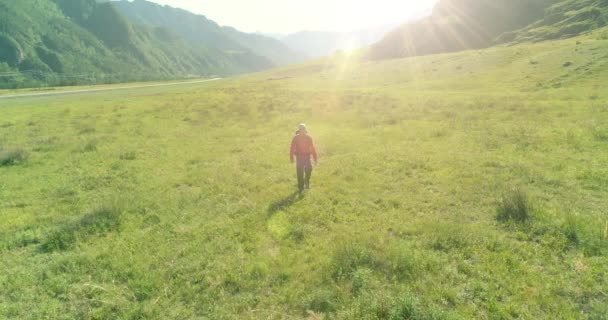 Volo sopra Zaino escursionistico turistico passeggiando attraverso il campo di montagna verde. Enorme valle rurale al giorno d'estate. — Video Stock