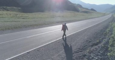 Asfalt yolda yürüyen otostopçu turist üzerinden uçuş. Yaz günü büyük bir kırsal vadi. Sırt çantalı gezgin..