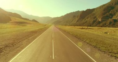 Güneşli yaz sabahında dağ yolu ve çayır üzerinde alçak hava uçuşları..
