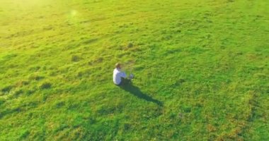 Yeşil çimlerin üzerinde sarı kırsal alanda not defteri olan bir adamın etrafında alçak yörünge uçuşları..