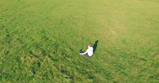 Lage baanvlucht rond mens op groen gras met notitieblok op geel landelijk veld. — Stockvideo