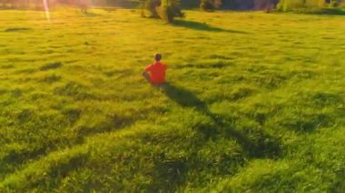 Yeşil çimlerde spor yogacısı üzerinde alçak irtifa radyal uçuş. Dağda gün batımı.