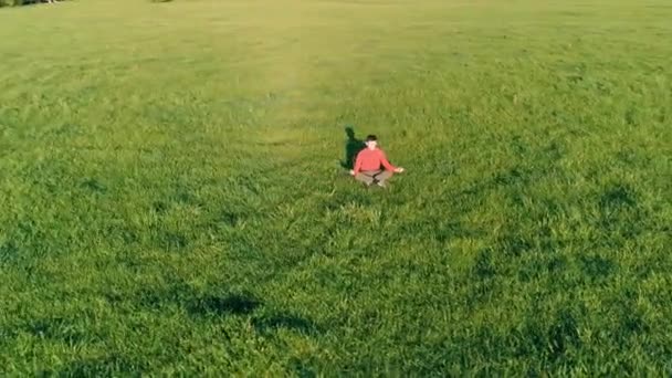 Lage hoogte radiale vlucht over sport yoga man op perfect groen gras. Zonsondergang in de bergen. — Stockvideo