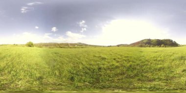 360 VR 'lık güzel bir dağ çayırı zaman dilimi. Yaz ya da sonbahar zamanında. Bulutlar, yeşil çimenler ve güneş ışınları.