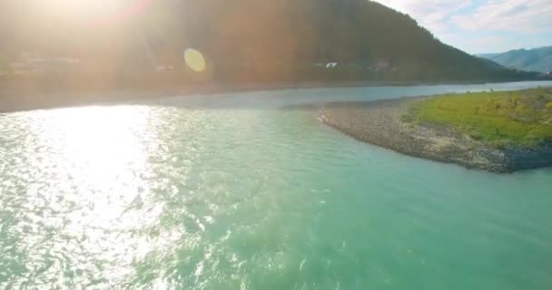 Vol à basse altitude au-dessus d'une rivière de montagne fraîche et rapide avec des rochers au soleil matin d'été. — Video