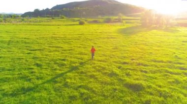 Mükemmel yeşil çayır üzerinde uçan bir sporcu. Dağda gün batımı