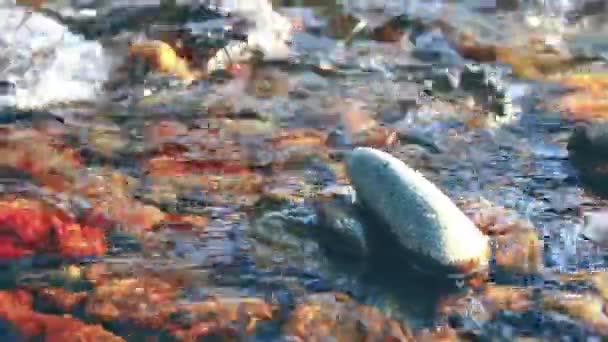 Dolly-Slider-Aufnahme des plätschernden Wassers in einem Gebirgsfluss in Waldnähe. Nasse Felsen und Sonnenstrahlen. Horizontale stetige Bewegung. — Stockvideo