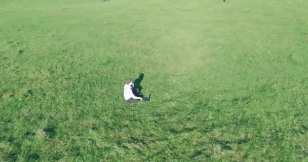 Lage baanvlucht rond mens op groen gras met notitieblok op geel landelijk veld. — Stockvideo