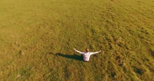 Penerbangan orbital rendah di sekitar manusia di rumput hijau dengan buku catatan pad di bidang pedesaan kuning. — Stok Video