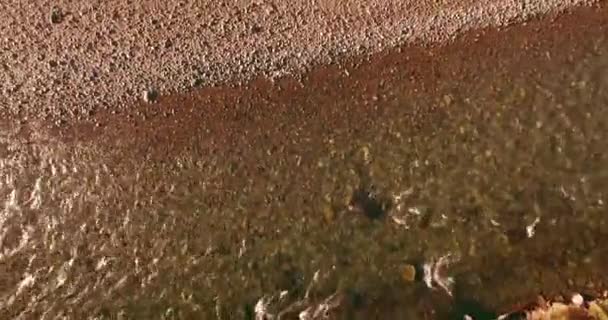 Vol à basse altitude au-dessus d'une rivière de montagne fraîche et rapide avec des rochers au soleil matin d'été.