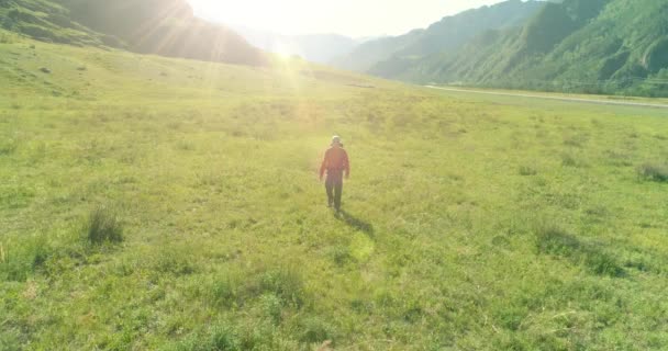 Volo sopra Zaino escursionistico turistico passeggiando attraverso il campo di montagna verde. Enorme valle rurale al giorno d'estate. — Video Stock