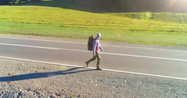 Flyg över liftare turist promenader på asfalterad väg. Enorm lantlig dal på sommardagen. Ryggsäck vandring kille. — Stockvideo