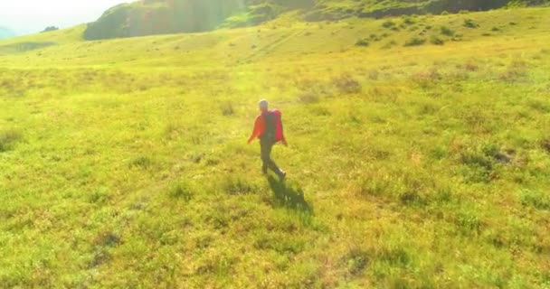 Terbang di atas Backpack hiking turis berjalan melintasi lapangan gunung hijau. Besar lembah pedesaan pada hari musim panas. — Stok Video