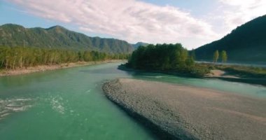 4k UHD hava görüntüsü. Güneşli yaz sabahında taze soğuk dağ nehri üzerinde alçak uçuş. Horisont 'ta yeşil ağaçlar ve güneş ışınları