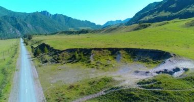 Güneşli yaz sabahında havadan kırsal dağ yolu ve çayır. Asfalt karayolu ve nehir.