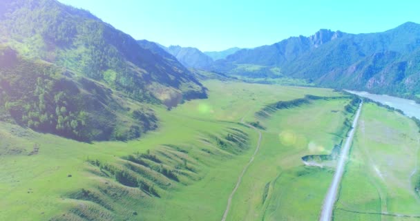 Route de montagne rurale aérienne et prairie au matin ensoleillé d'été. Asphalte autoroute et rivière. — Video