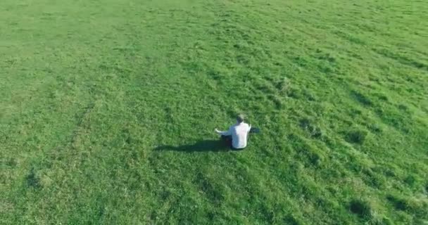 Lage baanvlucht rond mens op groen gras met notitieblok op geel landelijk veld. — Stockvideo