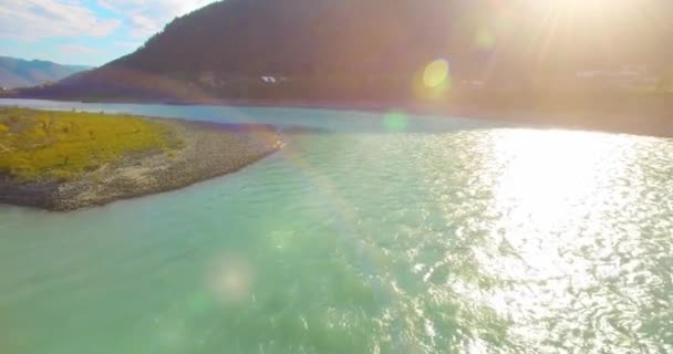 Vol à basse altitude au-dessus d'une rivière de montagne fraîche et rapide avec des rochers au soleil matin d'été. — Video