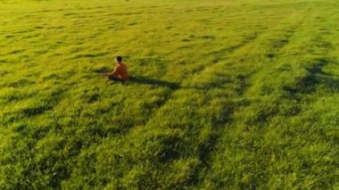 Yeşil çimlerde spor yogacısı üzerinde alçak irtifa radyal uçuş. Dağda gün batımı.