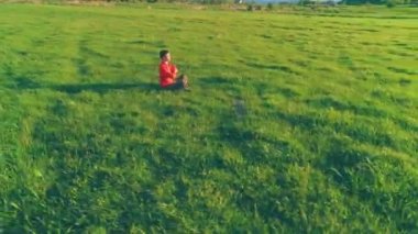 Yeşil çimlerde spor yogacısı üzerinde alçak irtifa radyal uçuş. Dağda gün batımı.