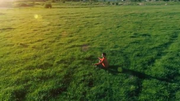 Vuelo radial de baja altitud sobre el hombre del yoga del deporte en hierba verde perfecta. Puesta de sol en montaña. — Vídeos de Stock