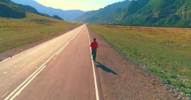 Voo de baixa altitude na frente do homem desportivo na estrada de asfalto perfeito — Vídeo de Stock