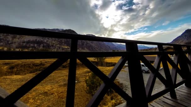 Timelapse van houten hek op hoog terras bij berglandschap met wolken. Horizontale schuifbeweging — Stockvideo