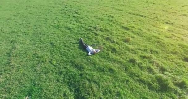 Lage baanvlucht rond mens op groen gras met notitieblok op geel landelijk veld. — Stockvideo