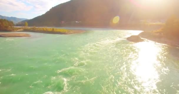 Vol à basse altitude au-dessus d'une rivière de montagne fraîche et rapide avec des rochers au soleil matin d'été. — Video