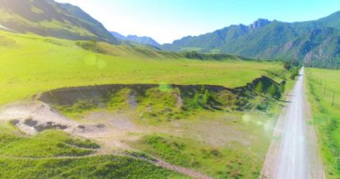 Güneşli yaz sabahında havadan kırsal dağ yolu ve çayır. Asfalt karayolu ve nehir.
