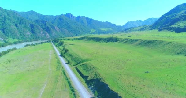 Luchtfoto landelijke bergweg en weide op zonnige zomerochtend. Asfaltweg en rivier. — Stockvideo