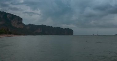 Kumsalda ve teknelerle deniz manzarasında yağmur bulutları hızlanıyor. Okyanusta tropik fırtına.