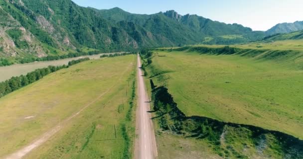 Luftlinie ländliche Bergstraße und Wiese an einem sonnigen Sommermorgen. Asphaltstraße und Fluss. — Stockvideo