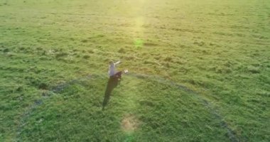 Yeşil çimlerin üzerinde sarı kırsal alanda not defteri olan bir adamın etrafında alçak yörünge uçuşları..