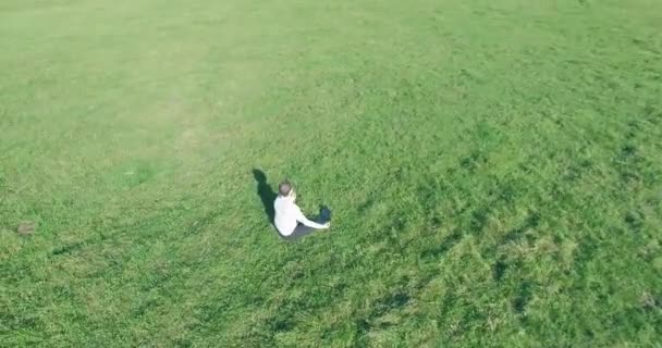 Lage baanvlucht rond mens op groen gras met notitieblok op geel landelijk veld. — Stockvideo