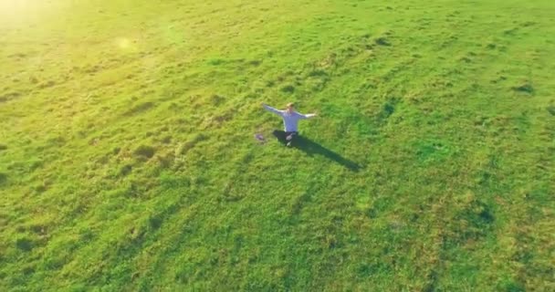 Vuelo orbital bajo alrededor del hombre sobre hierba verde con bloc de notas en el campo rural amarillo. — Vídeos de Stock