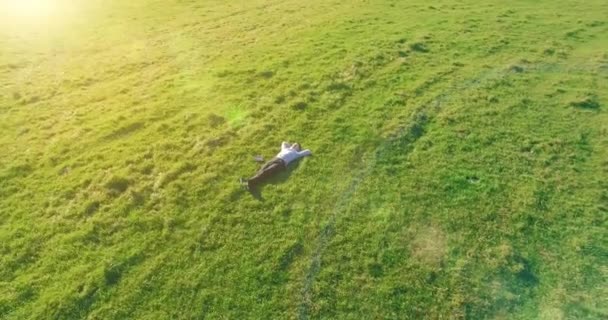Lage baanvlucht rond mens op groen gras met notitieblok op geel landelijk veld. — Stockvideo