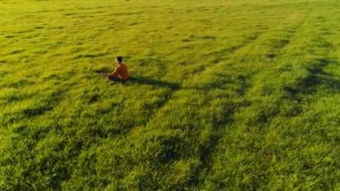 Yeşil çimlerde spor yogacısı üzerinde alçak irtifa radyal uçuş. Dağda gün batımı.