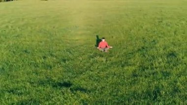 Yeşil çimlerde spor yogacısı üzerinde alçak irtifa radyal uçuş. Dağda gün batımı.