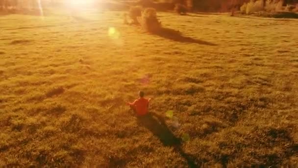Vol radial à basse altitude au-dessus du yoga sportif homme à l'herbe verte parfaite. Coucher de soleil en montagne. — Video